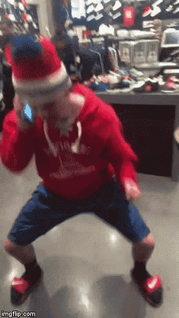 a man in a santa hat is dancing in a store while talking on a cell phone