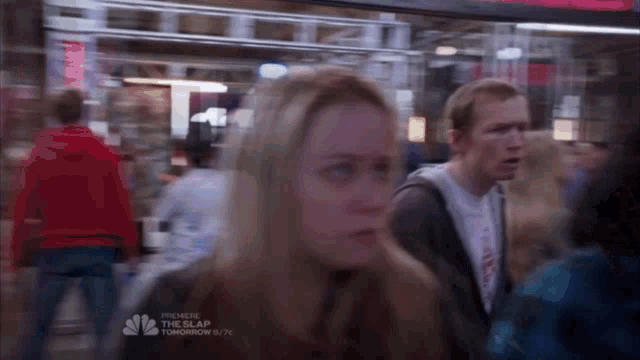a blurry picture of people walking in a crowd with a nbc advertisement in the corner