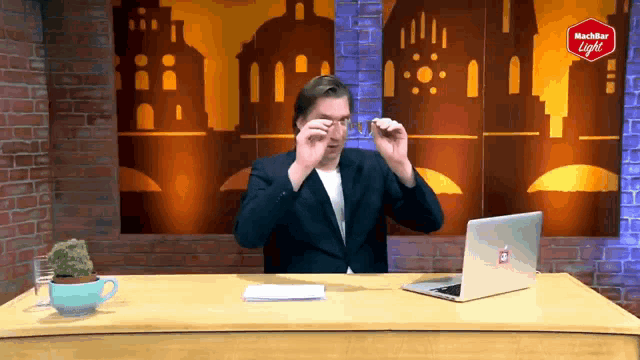 a man is sitting at a desk with a laptop and a sign that says nachter light