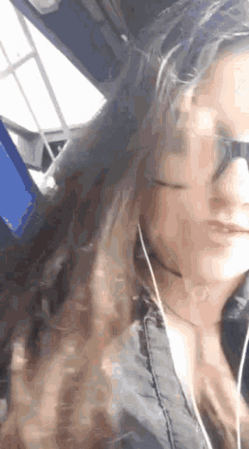 a woman wearing sunglasses and earphones is sitting in a car .