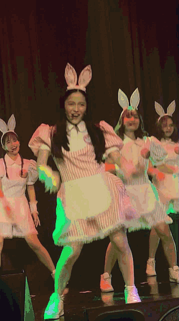 a girl with bunny ears on her head is dancing on stage