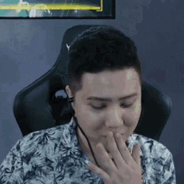 a man is sitting in a chair covering his mouth with his hand while playing a video game .