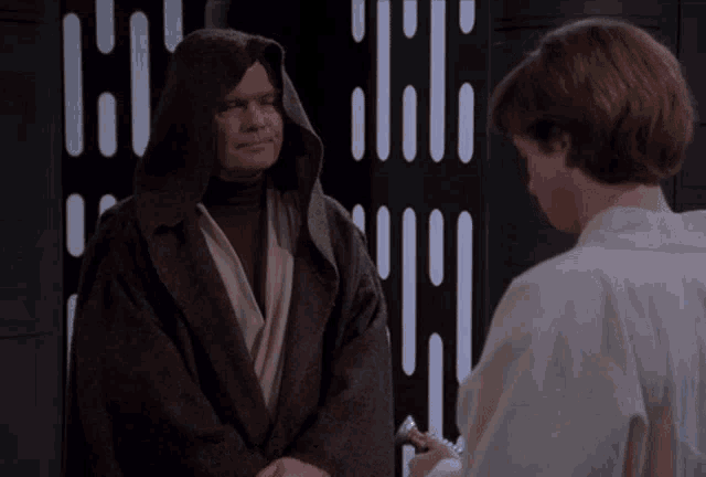 a man in a robe with a hood stands next to a boy in a white shirt