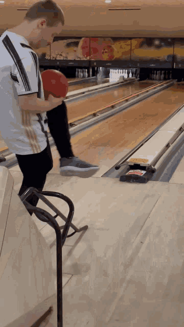 a man holding a bowling ball in a bowling alley with a sign that says ' strike ' on it