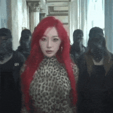 a woman with red hair is wearing a leopard print top and standing in a hallway with a group of people .