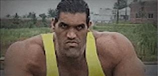 a man with very large muscles is wearing a yellow tank top and making a funny face .