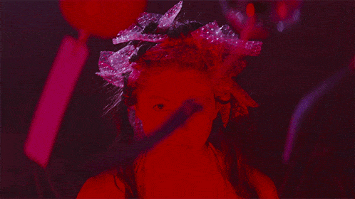 a woman wearing a red headpiece with a white light shining through it
