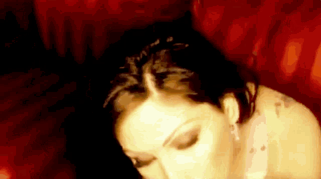 a woman is laying on a red couch with her eyes closed and a man is giving her a blowjob .