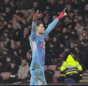 a man in a blue shirt is standing in front of a crowd with his arms crossed