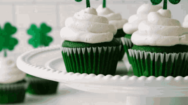 green cupcakes with white frosting on a white plate with shamrocks in the background