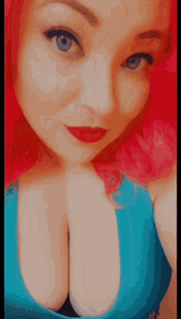 a woman with pink hair and blue eyes is wearing a blue tank top