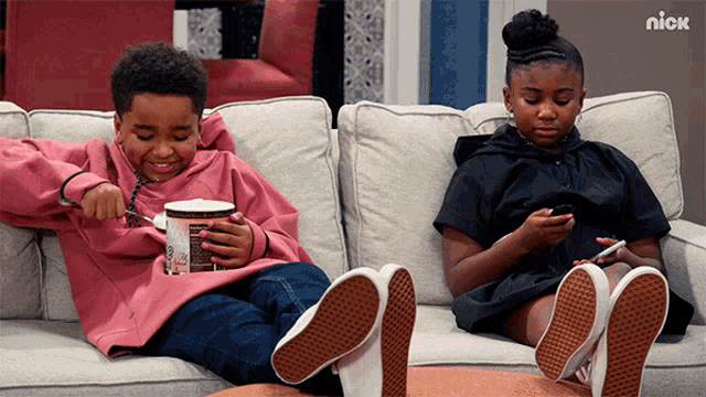 a boy and a girl are sitting on a couch with a nick logo in the corner