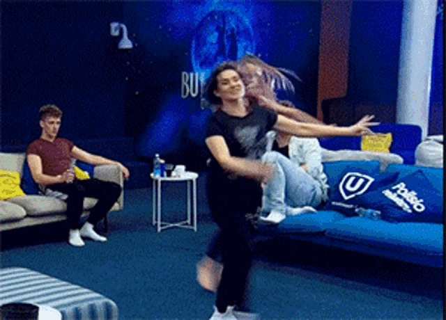 a group of people are dancing in a living room with a blue pillow that says pablo