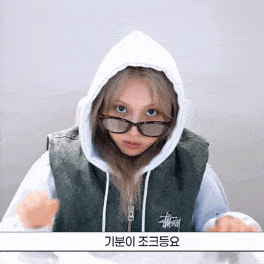 a girl wearing glasses and a hoodie with a foreign language on the bottom