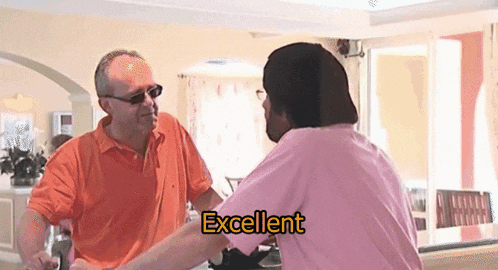 a man in a pink shirt says excellent to another man in an orange shirt
