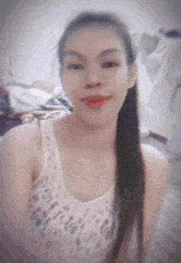 a woman with long hair is wearing a white tank top and red lipstick