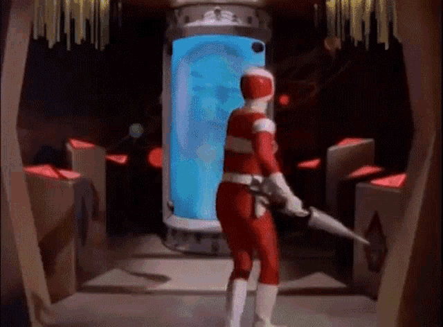 a man in a red ranger costume is holding a gun in front of a blue tank .