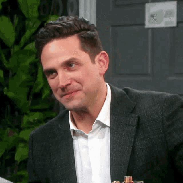 a man wearing a suit and a white shirt is smiling
