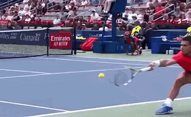 a tennis player is swinging a racket at a tennis ball on a court sponsored by emirates