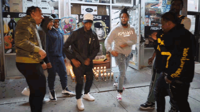 a group of men are dancing in front of a store that says gr