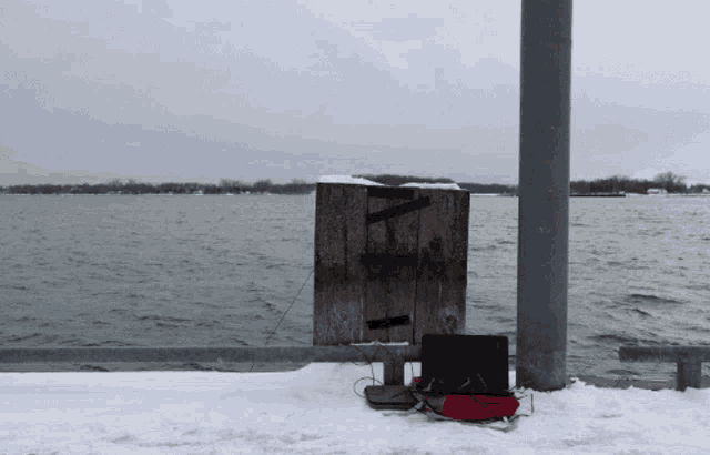 a laptop sits on a snow covered dock near the water