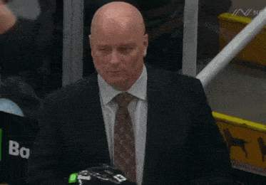 a man in a suit and tie holds a helmet that says bank on it