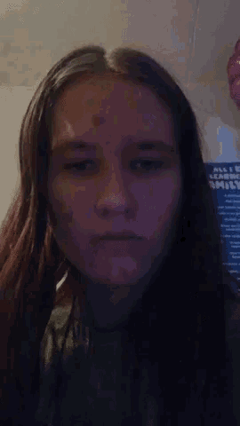 a girl with long hair is making a funny face in front of a poster that says shark sixty .