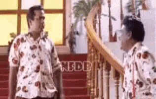 two men are standing next to each other on a set of stairs and talking .