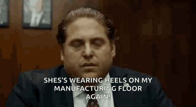 a man in a suit and tie is sitting at a table with his eyes closed and talking .