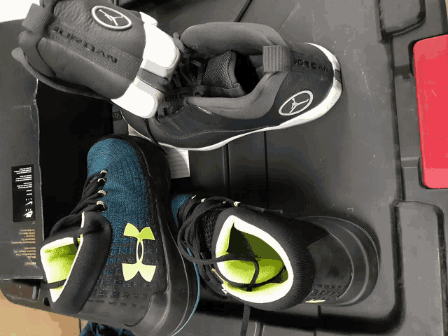 a pair of under armour shoes laying on top of a black box