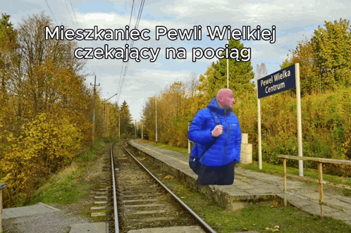 a man in a blue jacket stands in front of a sign that says pewi wielka centrum