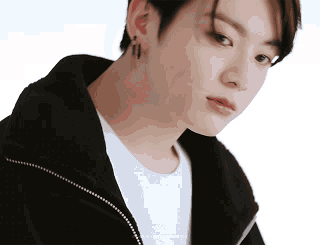 a close up of a person 's face with a white shirt and a black jacket with the letters 000 on the bottom