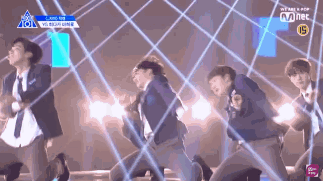 a group of young men are dancing in front of a mnet banner
