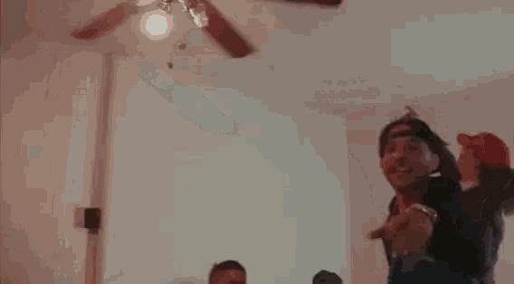 a group of people are standing in a room with their arms outstretched and pointing at something .