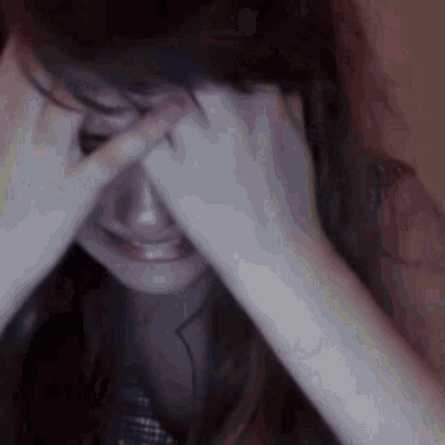 a woman is crying with her hands over her face
