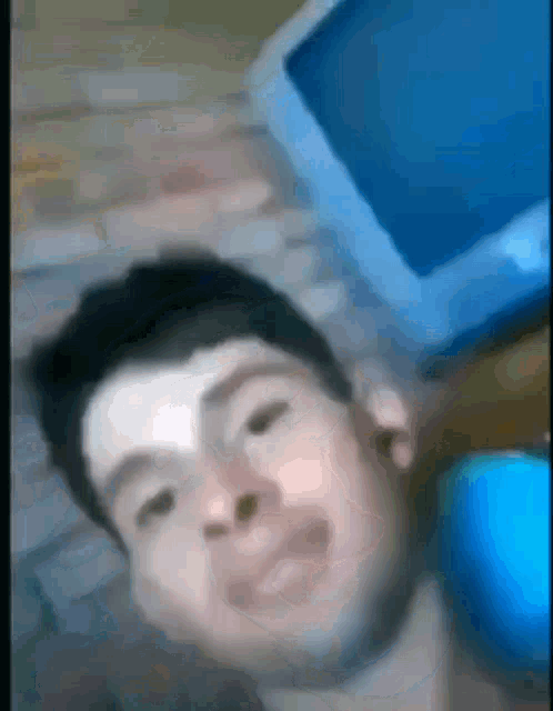 a blurry picture of a man laying on a bed next to a laptop computer .