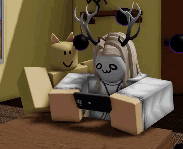 a girl with antlers is sitting on a table looking at her phone