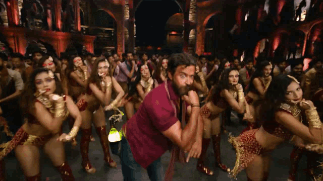 a man in a maroon shirt stands in front of a crowd of women