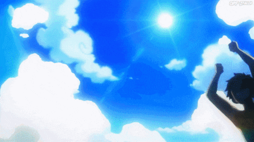 a person with their arms in the air in front of a blue sky with clouds
