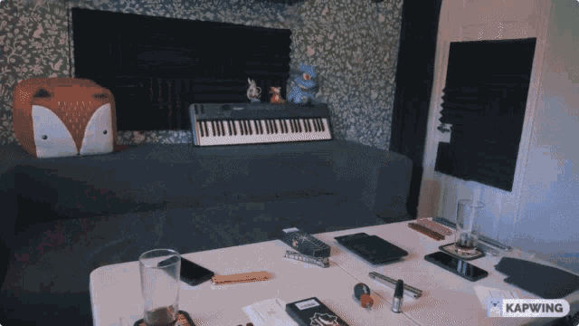 a keyboard sits on a couch in a room with a kapwing logo on the table