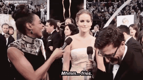 a woman in a white dress is being interviewed by a man in a tuxedo at an event .