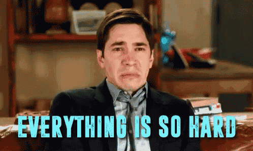 a man in a suit and tie is sitting on a couch with the words everything is so hard behind him