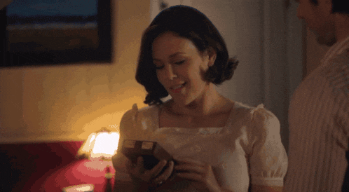 a woman in a white shirt is holding a box in her hand