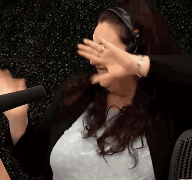 a woman wearing headphones is covering her face with her hand