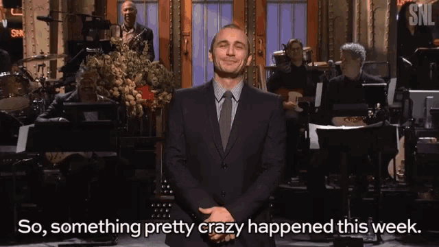 a man in a suit and tie is standing in front of a snl sign