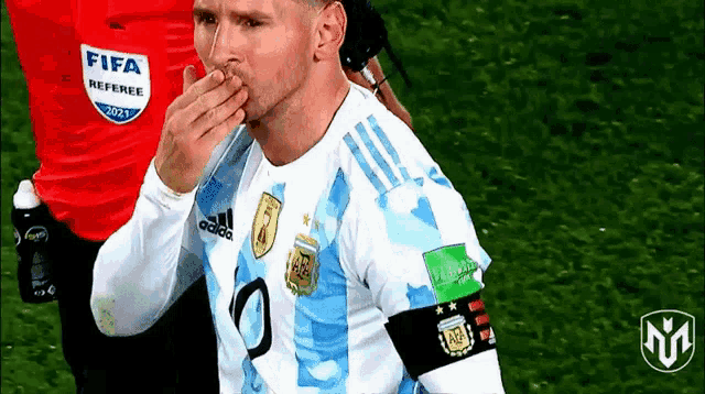 a soccer player is blowing a kiss while wearing a fifa referee shirt .