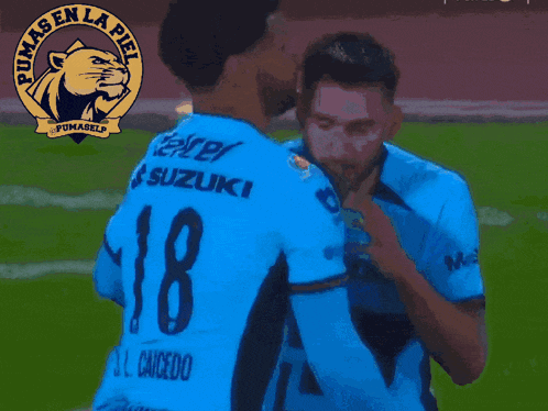 a man in a blue pumas en la pie jersey applauds on a soccer field