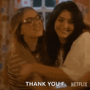 two girls are hugging each other and smiling while sitting on a bed .