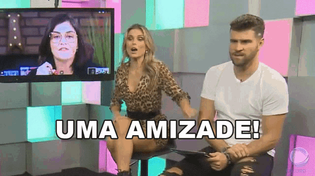 a man and a woman are sitting in front of a television with the words uma amizade written below them