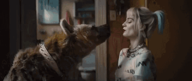 harley quinn is kissing a hyena in a room .